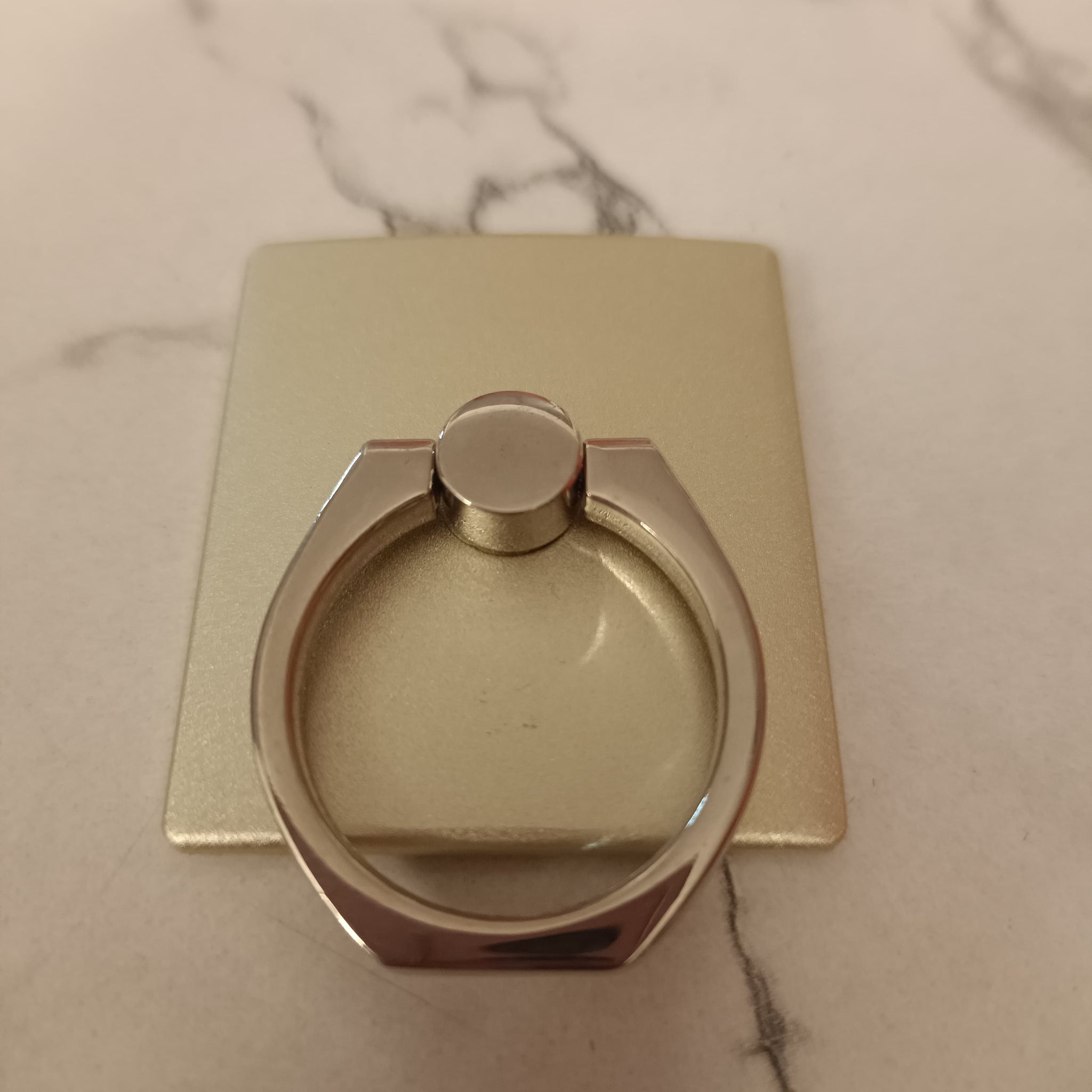 A 360° rotating phone ring holder attached to the back of a smartphone, offering a secure grip and functioning as a stand for hands-free use. Compatible with all smartphone models.